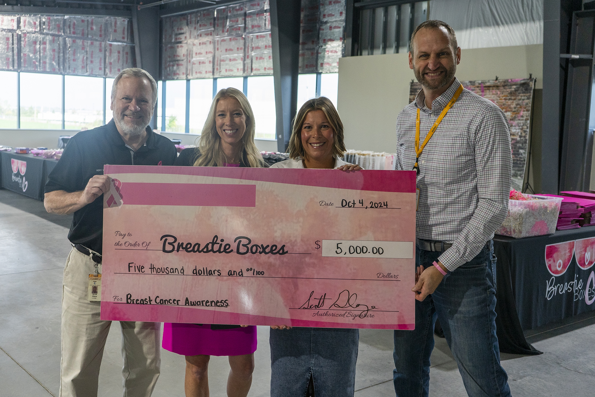 four people holding a large donation check for Breastie Boxes